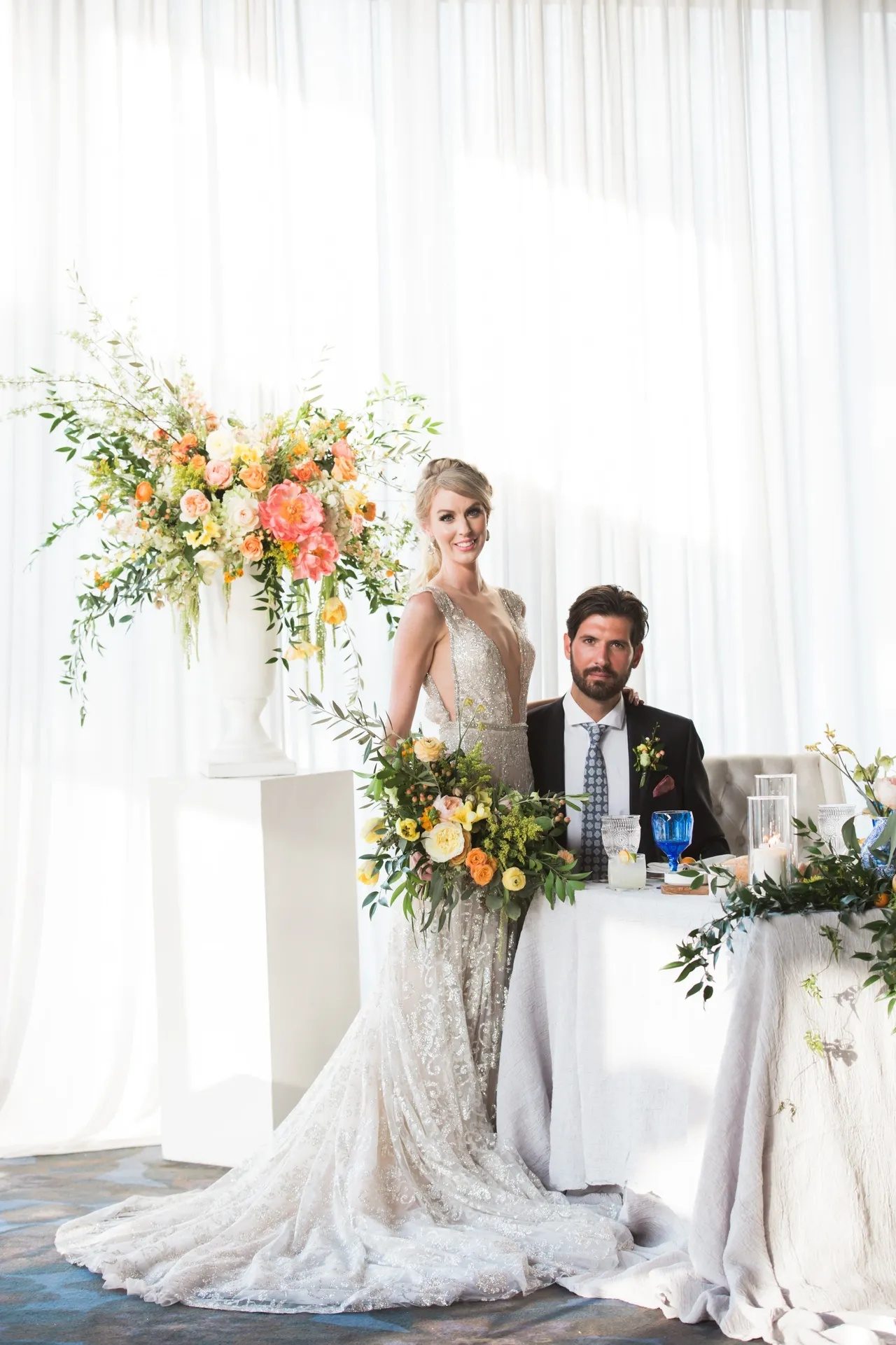 The couple together at the sweetheart table, with the floral installation behind them.